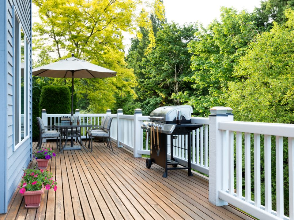 deck during the summer with an umbrella and grill on it